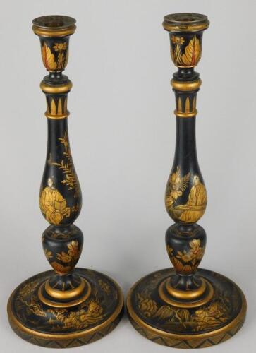 A pair of early 20thC black japanned turned wooden candlesticks