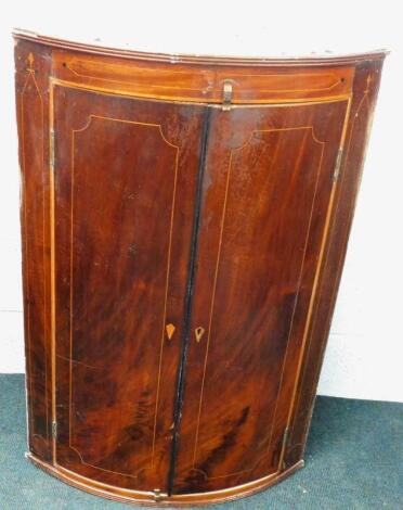 A George III mahogany bow fronted hanging corner cabinet.