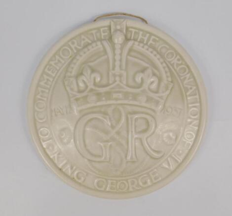 An ivory monochrome pottery circular wall plaque to commemorate The Coronation of King George VI