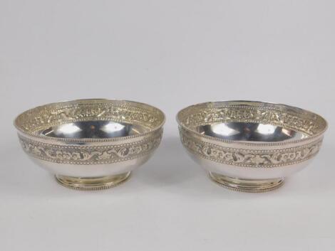 A pair of Indian bowls embossed with a band of flowers