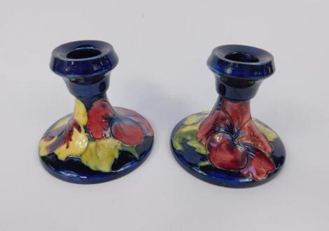 A pair of Moorcroft early 20thC pottery candlesticks decorated in the Hibiscus pattern