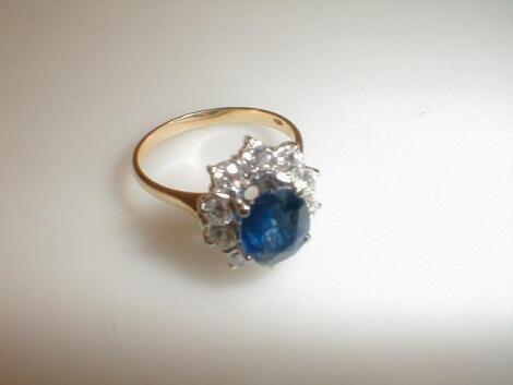 A diamond cluster ring with a sapphire blue central stone surround by ten diamonds