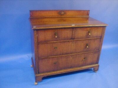 A beaded oak chest of two short and two long drawers on bracket feet