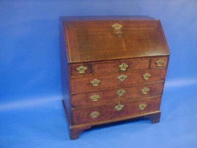 A George III oak bureau with fall flap revealing a fitted interior over