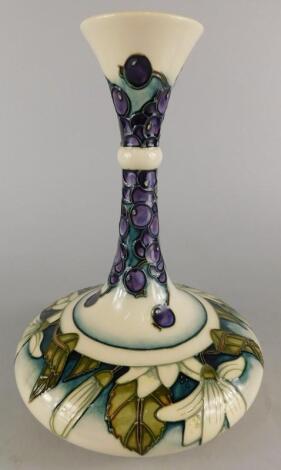 A Moorcroft pottery bottle shaped vase decorated with blue berries and flowers