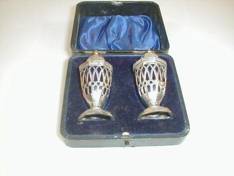 A cased pair of Edwardian silver pepperettes with pierced octagonal bodies