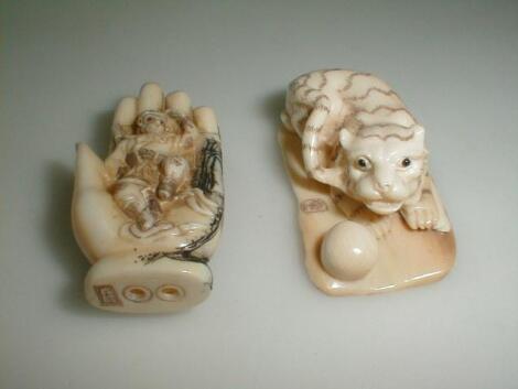 A Japanese ivory netsuke depicting a monkey seated in a large hand