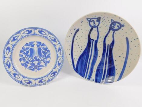 A studio pottery plate decorated in blue and white with stylised cats