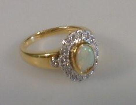 A ladies dress ring, a channel set oval opal surrounded by tiny diamonds