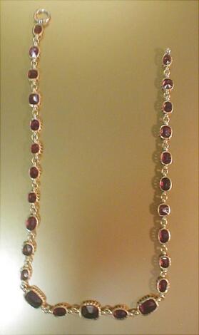 A necklace of graduated faceted claw set garnets