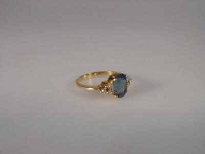 An oval dress ring set with a pale blue oval stone and set in yellow metal