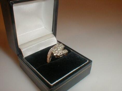 A ladies diamond set dress ring of two crossed over flower clusters with