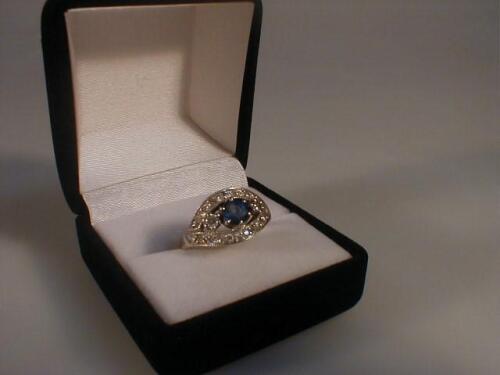 A diamond and sapphire set dress ring of a round central blue stone set