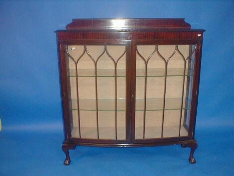 A 1920's mahogany bow front china cabinet with two glazed doors and ball and claw feet