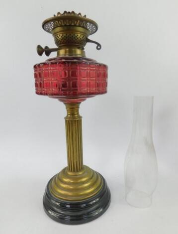 An early 20thC brass and cranberry glass oil lamp