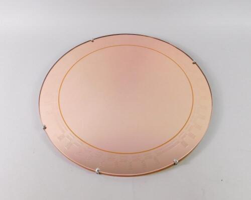 A mid 20thC circular pink glass wall mirror