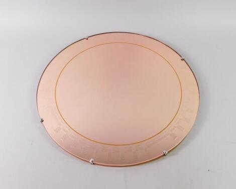 A mid 20thC circular pink glass wall mirror