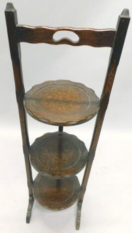 A carved oak three tier folding cake stand