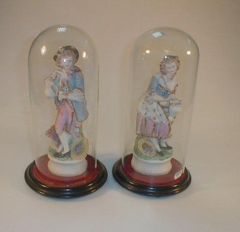 A pair of 19thC polychrome bisque figures of a young man and lady carrying flagons