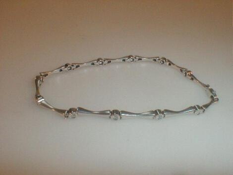 A white metal bracelet stamped 375 of bars connected by small collet set diamonds