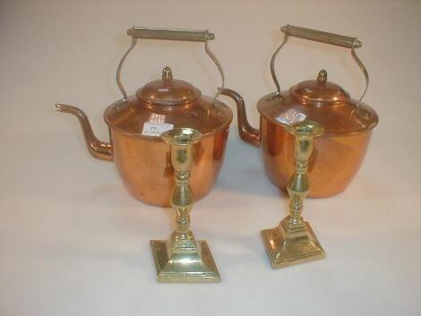 Two copper kettles and a pair of brass candlesticks