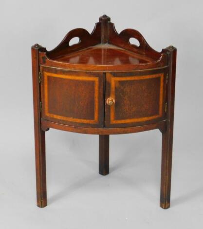 A George III bow fronted mahogany and cross banded corner washstand