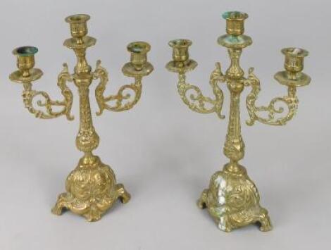 A pair of Continental cast brass three branch candelabra