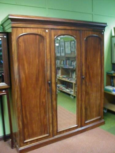 A Victorian mahogany triple wardrobe with mirrored centre door