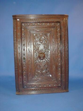 A Georgian carved oak hanging corner cupboard