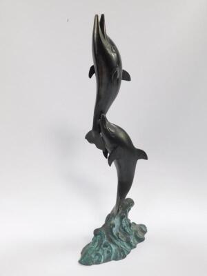 A late 20thC copper and bronzed copper sculpture modelled as a pair of leaping dolphins