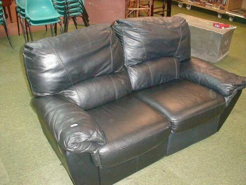 A black leather finished reclining two seater sofa