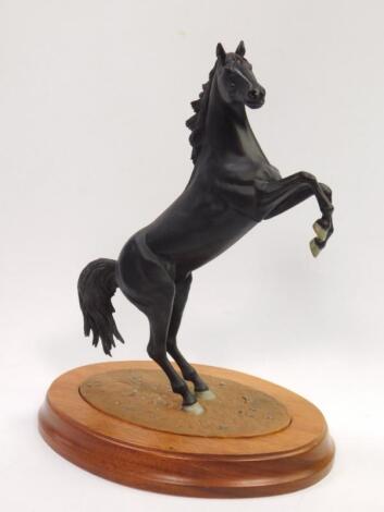 A cast metal sculpture of a rearing black stallion