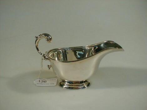 A George VI silver sauce boat with scroll handle and oval foot