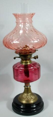 A Victorian cranberry glass and brass oil lamp