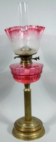 A Victorian cranberry glass and brass oil lamp