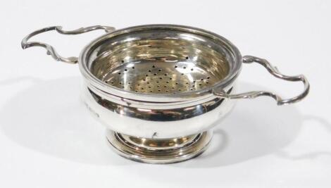 A silver tea strainer on stand