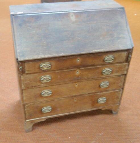 A George III oak bureau with fall flap resting on loppers over four graduated drawers