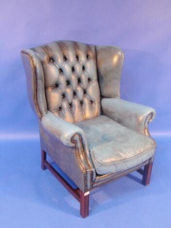 A blue leather effect finish button back wing armchair