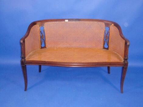 An Edwardian walnut curved two seater Boudoir sofa with caned back and