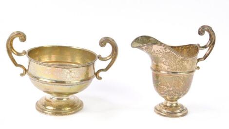 A George V silver helmet shaped cream jug and twin handled sugar bowl