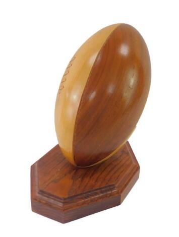 A carved bi-colour treen rugby ball