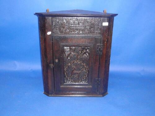 A carved oak hanging corner cupboard