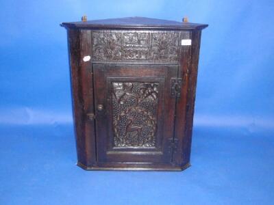 A carved oak hanging corner cupboard