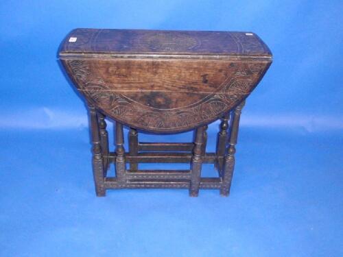 A carved oak gate leg table with drop leaves