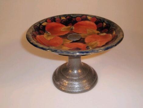 A Moorcroft pottery tazza on a swept planished pewter column and domed foot