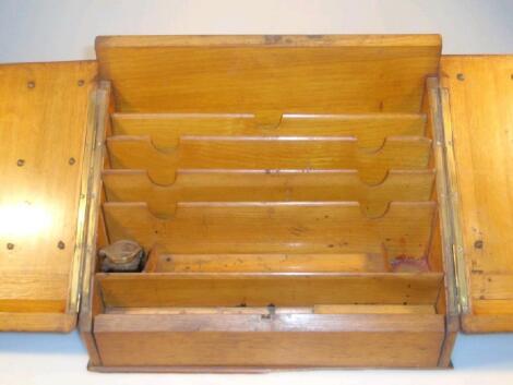 An oak table top stationery cabinet with twin sloping doors enclosing a