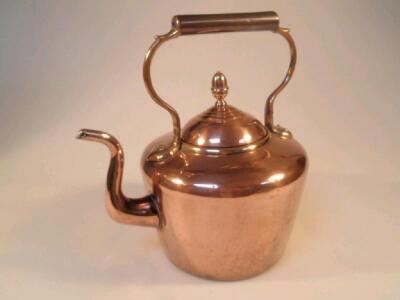 A copper kettle with brass mount and overhead handle