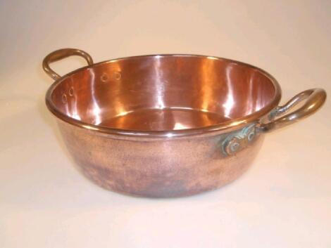 A 19thC copper dairy bowl of shallow circular form with a rolled rim and two handles