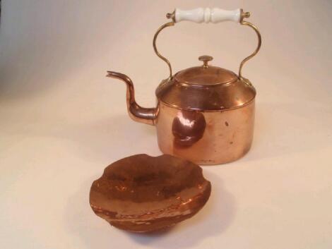 An oval copper kettle with a white ceramic and brass handle