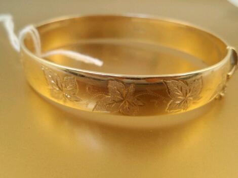 A 9ct gold hinged bangle with leaf decoration